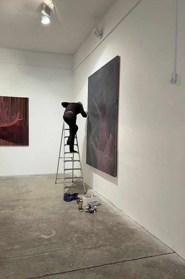 Thomas Nolden auf einer Leiter an einem großen Gemälde in einem weißen Ausstellungsraum